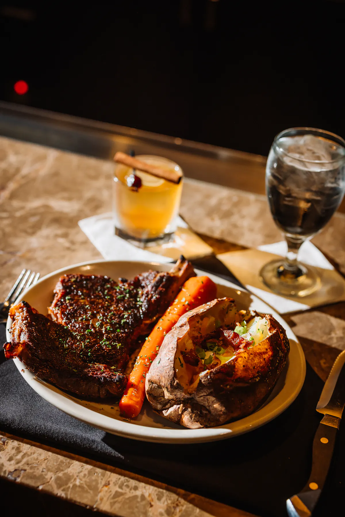 a plate of steak and potatoes with a drink